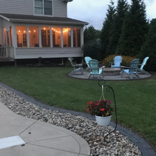 beige house with glass windows and a fire pit outside in the middle of the patio