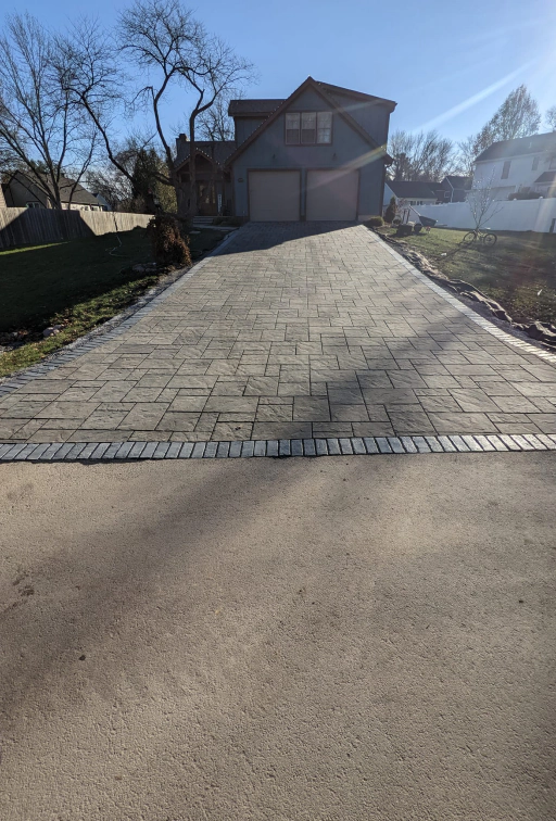 grey house with a drive path and a street on the front