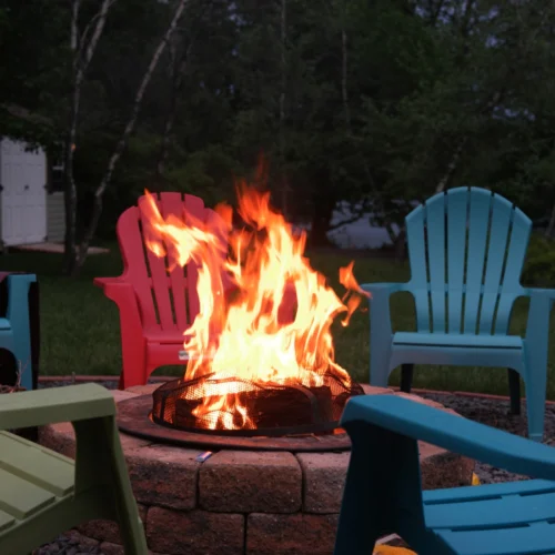 lighten fire pit with blue red and green wood chairs
