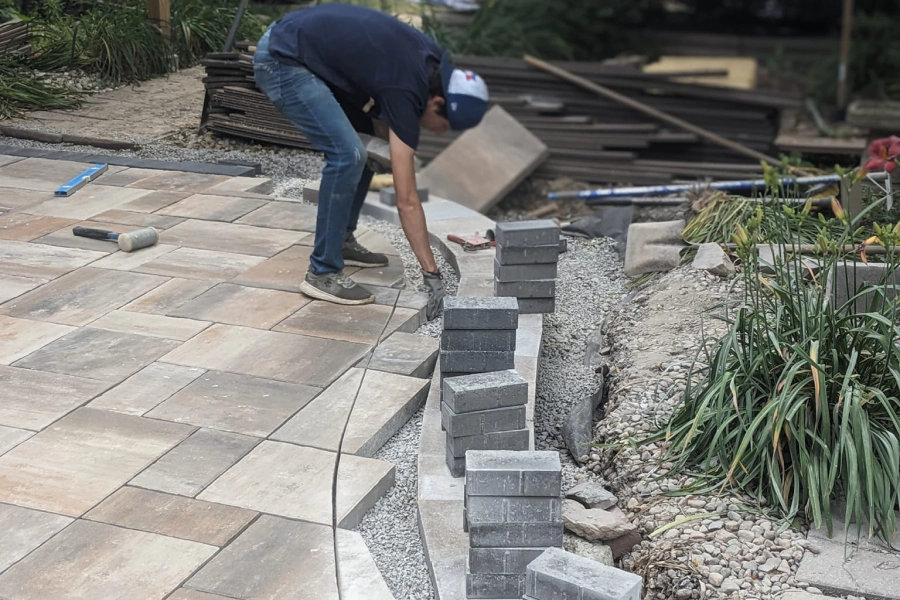 worker making a paving on a patio with plants at the right